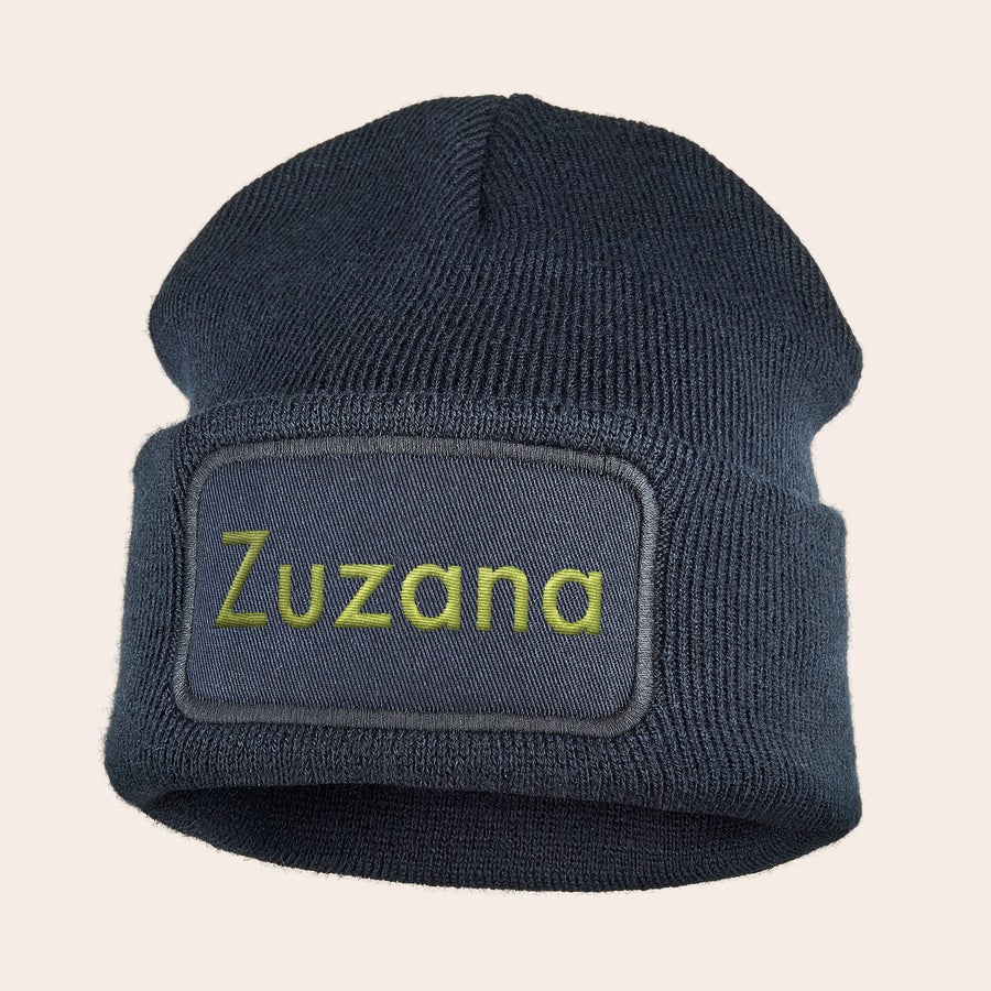 Vyšívaný klobouk Tmavě modrá pletená čepice s vyšitým jménem Zuzana žlutou barvou na přední straně.