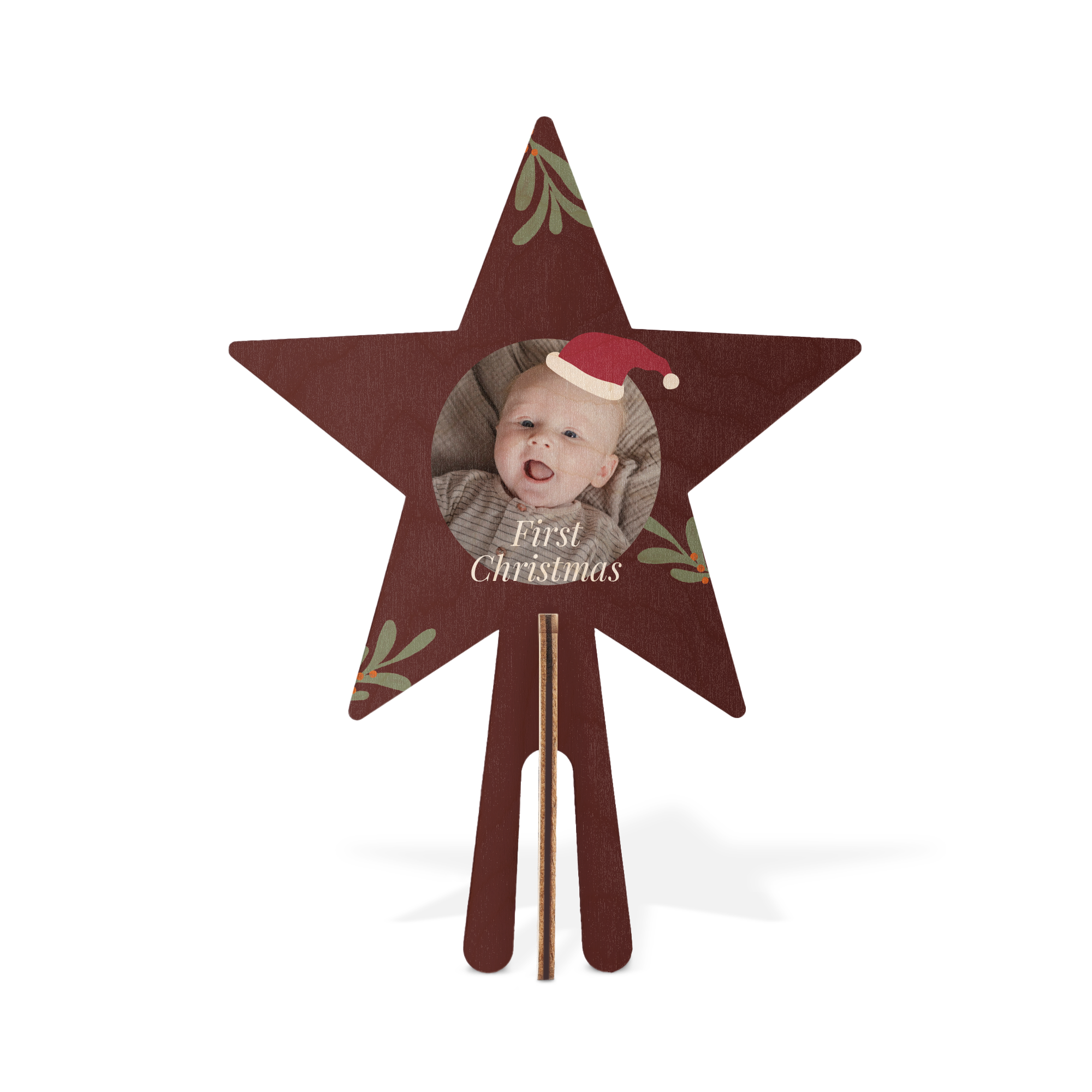 Rödbrun personlig trätopp med tryckt bild av ett barn i tomteluva och texten First Christmas, dekorerad med mistelkvistar. Topp för återanvändbar minijulgran.