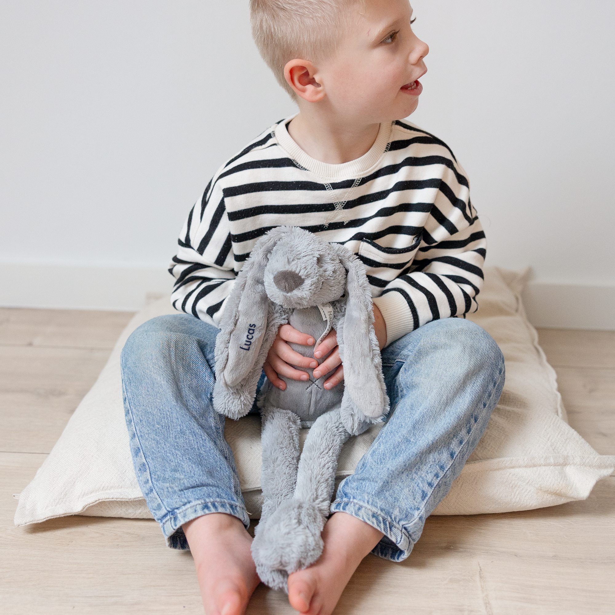 En pojke håller en grå Rabbit Richie gosedjur med namnet Lucas broderat på örat, perfekt för den lilla