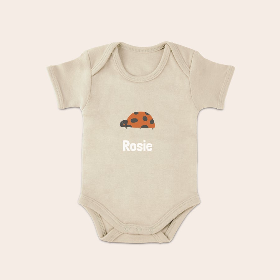 Otroška obleka Béžni kombinezon za dojenčke s potiskano piko in personaliziranim imenom Rosie.