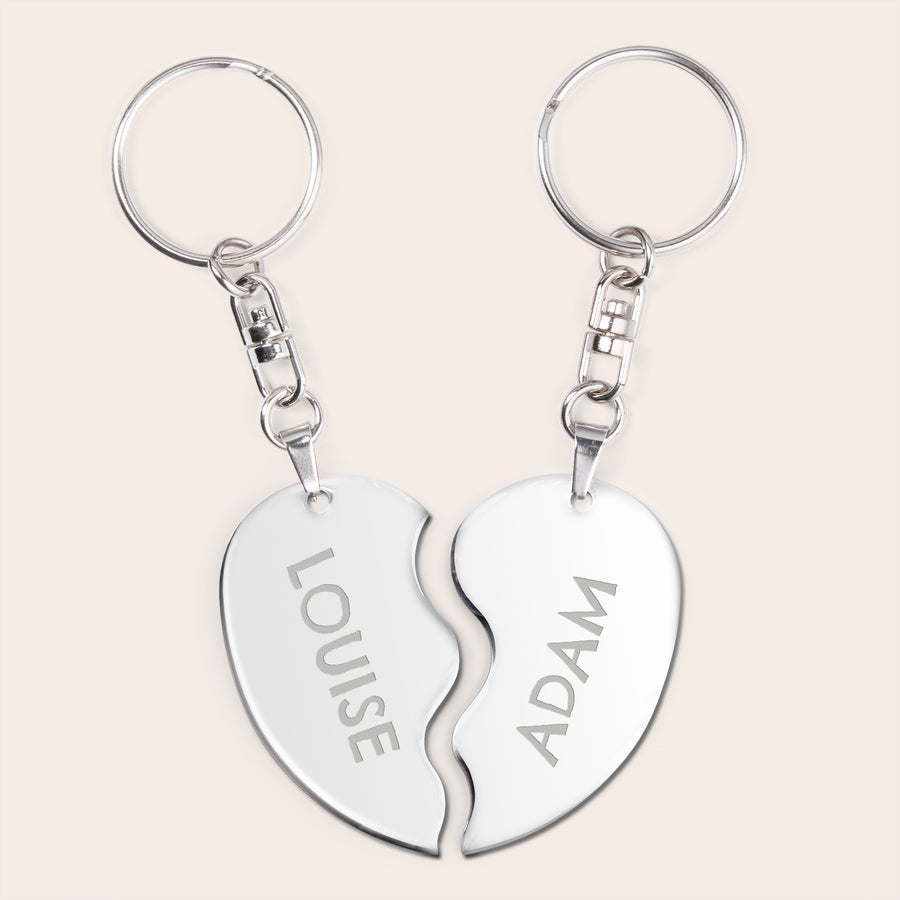 Breloc - Half Heart Două brelocuri metalice argintii în formă de inimă frântă, personalizate prin gravură cu numele "LOUISE" și "ADAM", un cadou pentru cuplu.
