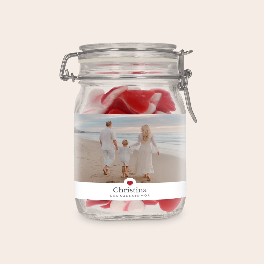 Personlig Glaskrukke med Slik Lav din egen glaskrukke med hjerteformet slik og personlig etikette. Den viser et foto af en familie på stranden og teksten Christina den sødeste mor