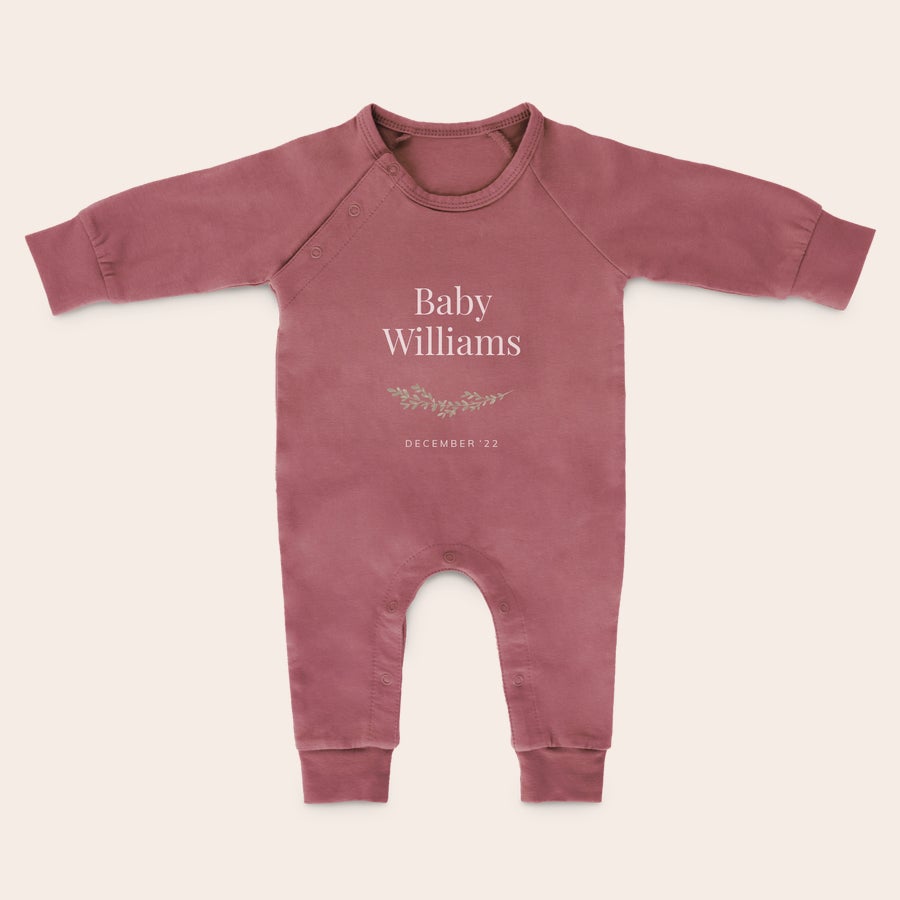 Babygrow Babygrow personalizado rosa com "Baby Williams" e "December '22" impresso em branco com folhagens.