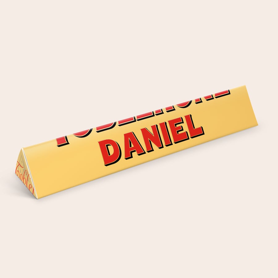 Toblerone med namn Personlig Toblerone med namn och bild, tryckt med namnet Daniel i rött på guldfärgad förpackning.