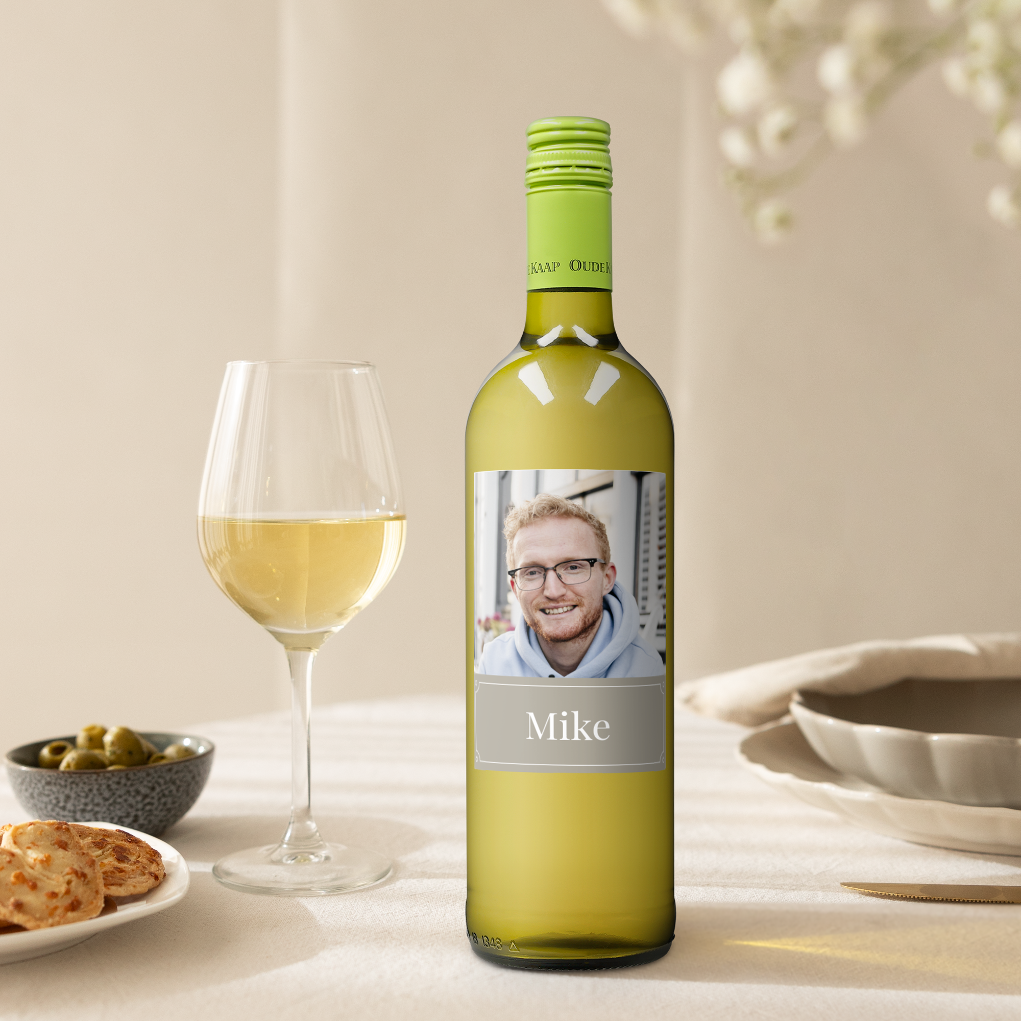 Oude Kaap white wine bottle with a personalized photo label and the name Mike printed on it, next to a wine glass.