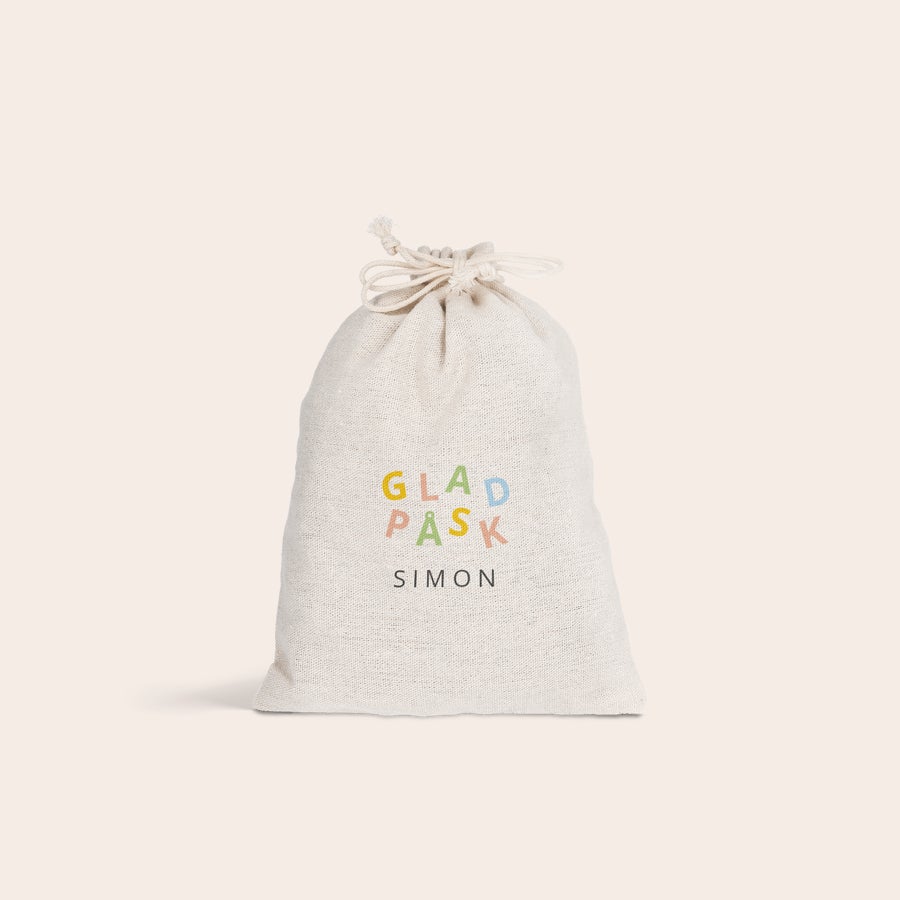 Presentpåse med dragsko - påsk En personlig presentpåse med dragsko i bomull-linne med tryckt text "Glad Påsk" i färgglada bokstäver och namnet "Simon" under. Gör påsken speciell med personliga presentpåsar med dragsko.