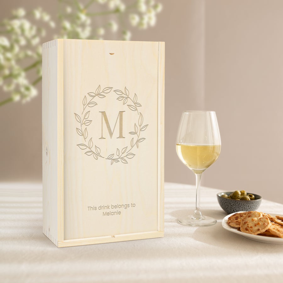Gepersonaliseerde wijnkist Houten wijnkist met een persoonlijke gravure van initiaal M, omringd door bladeren, en de tekst 'This drink belongs to Melanie'.
