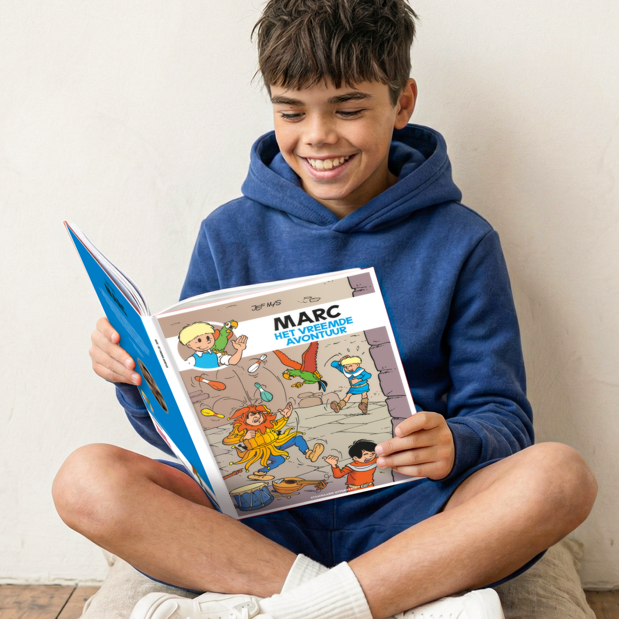 Lachende jongen leest een Persoonlijk stripboek - Jommeke Het vreemde avontuur (Hardcover) met de naam Marc op de voorkant, gepersonaliseerd met een naam.