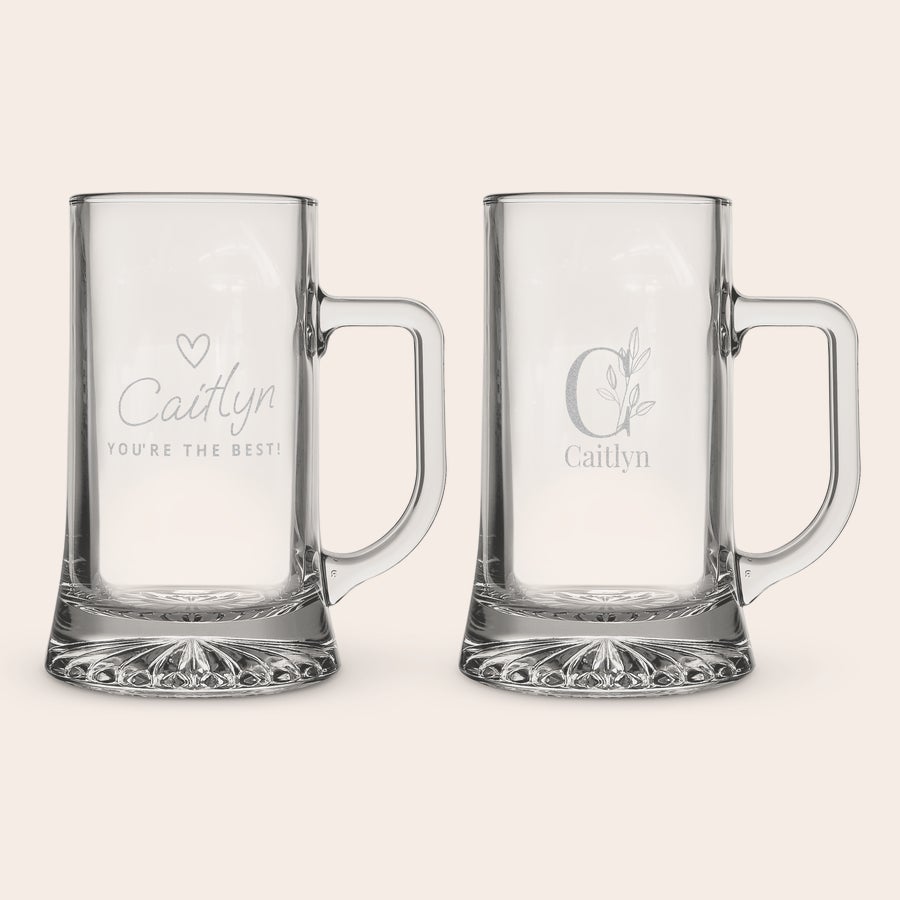 Caneca de cerveja de vidro gravado Duas canecas de vidro gravadas, uma com o nome "Caitlyn" e a frase "YOU'RE THE BEST!", a outra com a inicial "C" e o nome "Caitlyn" abaixo. Desfrute da sua bebida gelada favorita em uma caneca de vidro exclusiva e personalizada com seu nome!