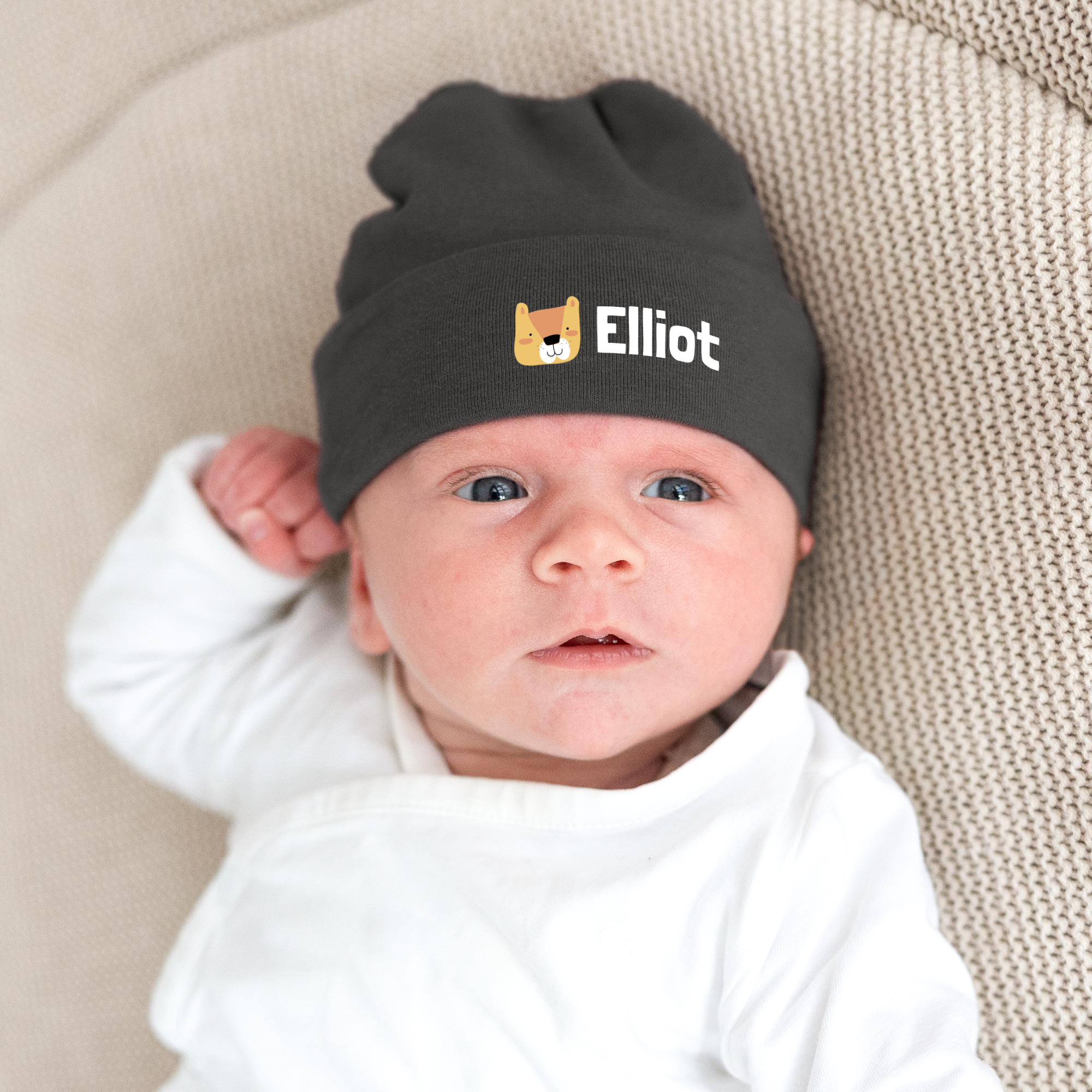 En söt babymössa med tryck i mörkgrått, prydd med namnet Elliot och ett tryckt hundansikte.