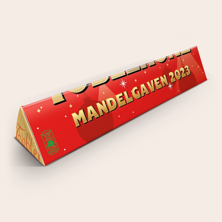 Toblerone med navn - Juletema Personlig Toblerone julechokoladebar med teksten MANDELGAVEN 2023, trykt på rød indpakning.