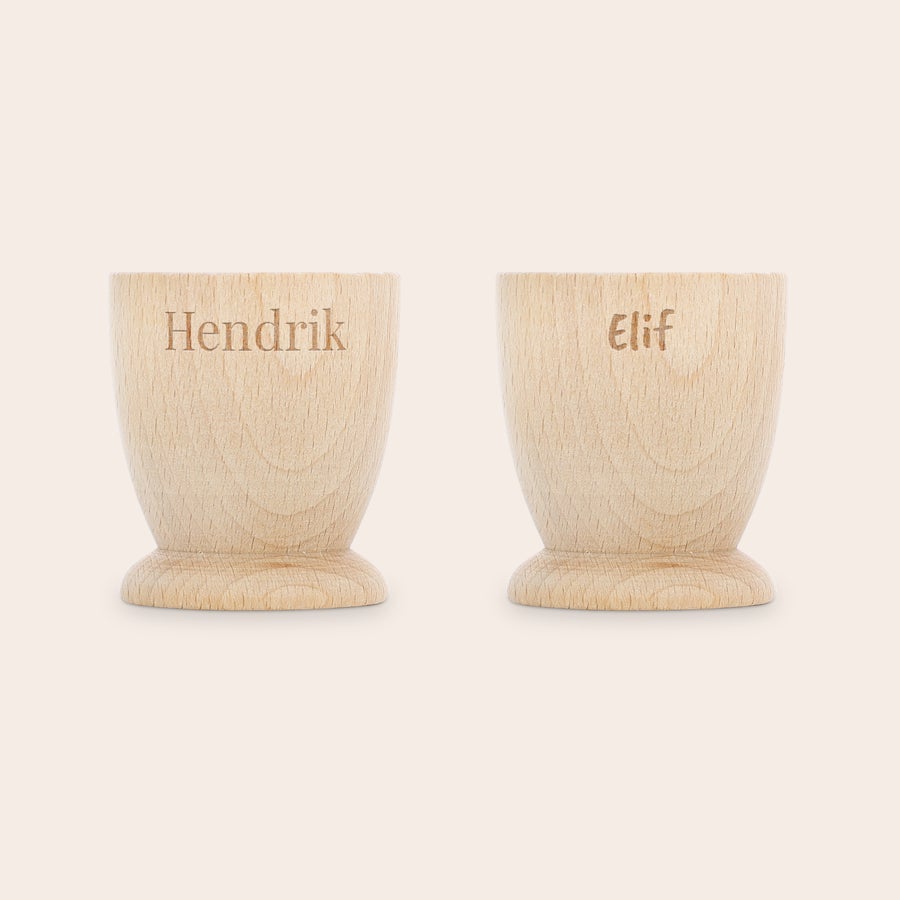 Eierbecher personalisiert Zwei personalisierte Eierbecher aus hellem Buchenholz, graviert mit den Namen Hendrik und Elif, um das Frühstück unvergesslich zu machen