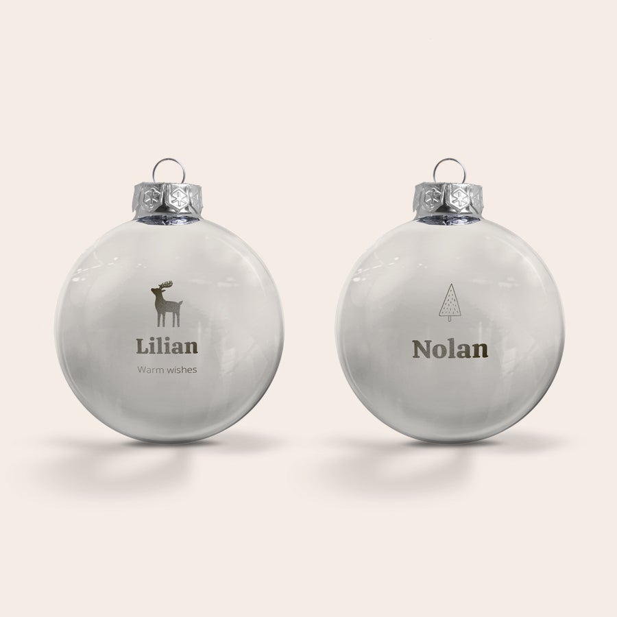 Quinquilharia de vidro com nome Dois enfeites de Natal de vidro personalizados, um com o nome Lilian e uma rena, e outro com o nome Nolan e uma árvore, gravados com um nome ou texto.