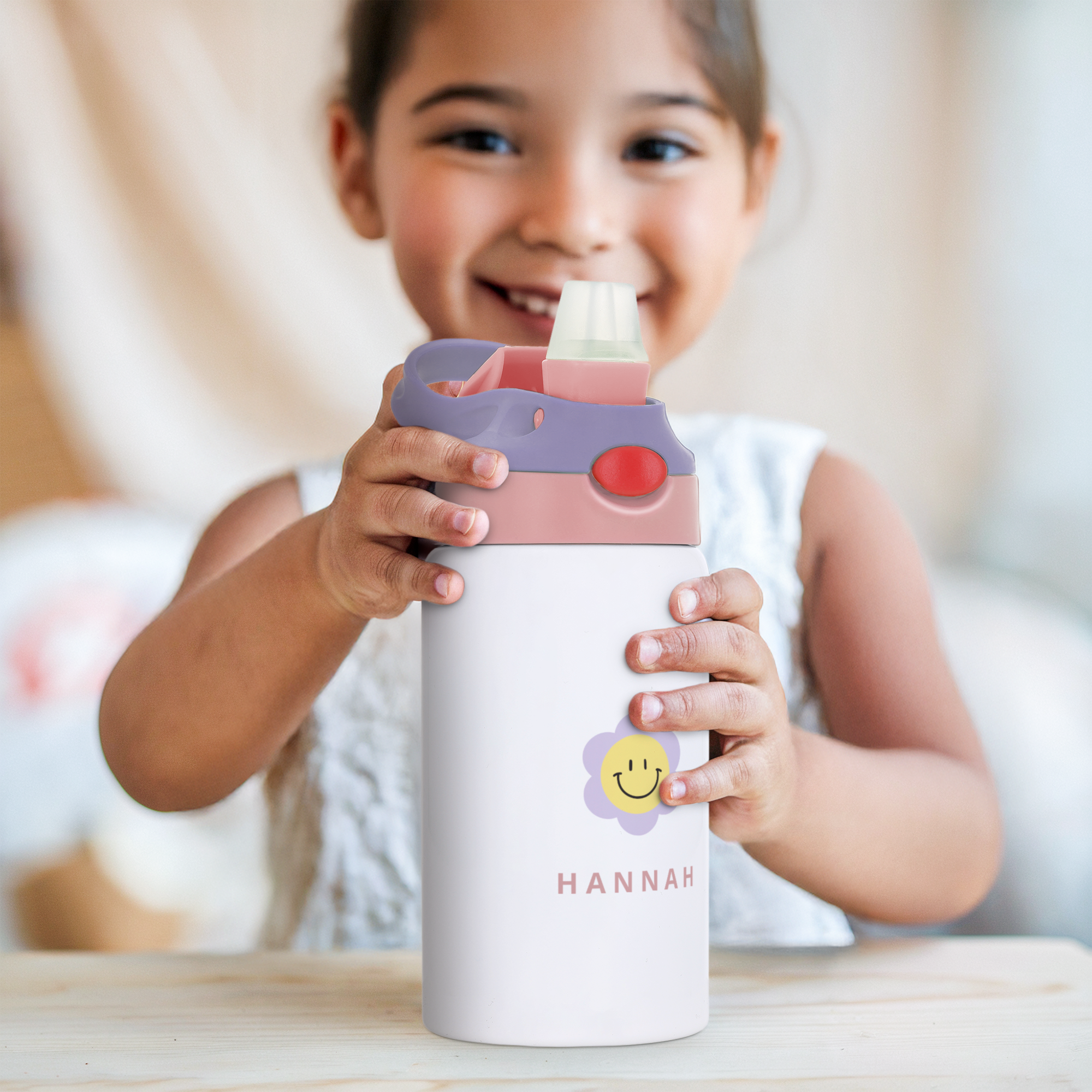 Garrafa de água infantil branca com tampa rosa e roxa, personalizada com o nome Hannah e flor sorridente.