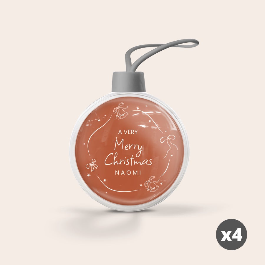 Läpinäkyvä joulupallo Anna lahjaksi itse luomasi joulupallo ruskealla sisuksella ja tekstillä "A Very Merry Christmas Naomi", valkoiset jouluaiheiset kuvitukset.