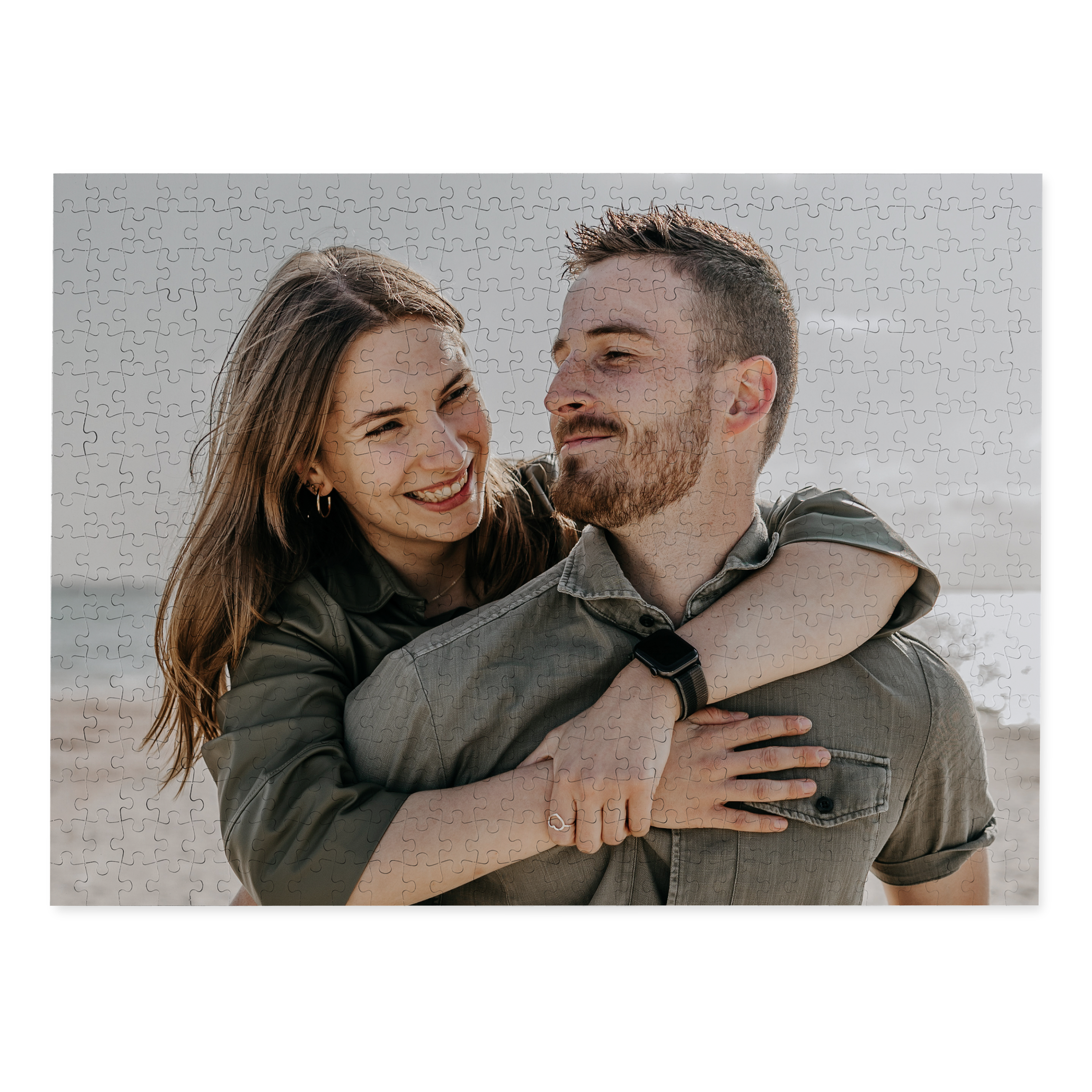 A personalised puzzle printed with a photo of a smiling couple hugging on the beach