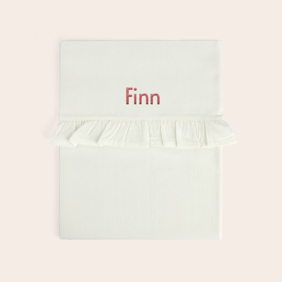 Broderet barneseng - Flæse Personaliseret lagen til vuggen i hvidt med flæsekant, broderet med navnet "Finn" i rød tråd