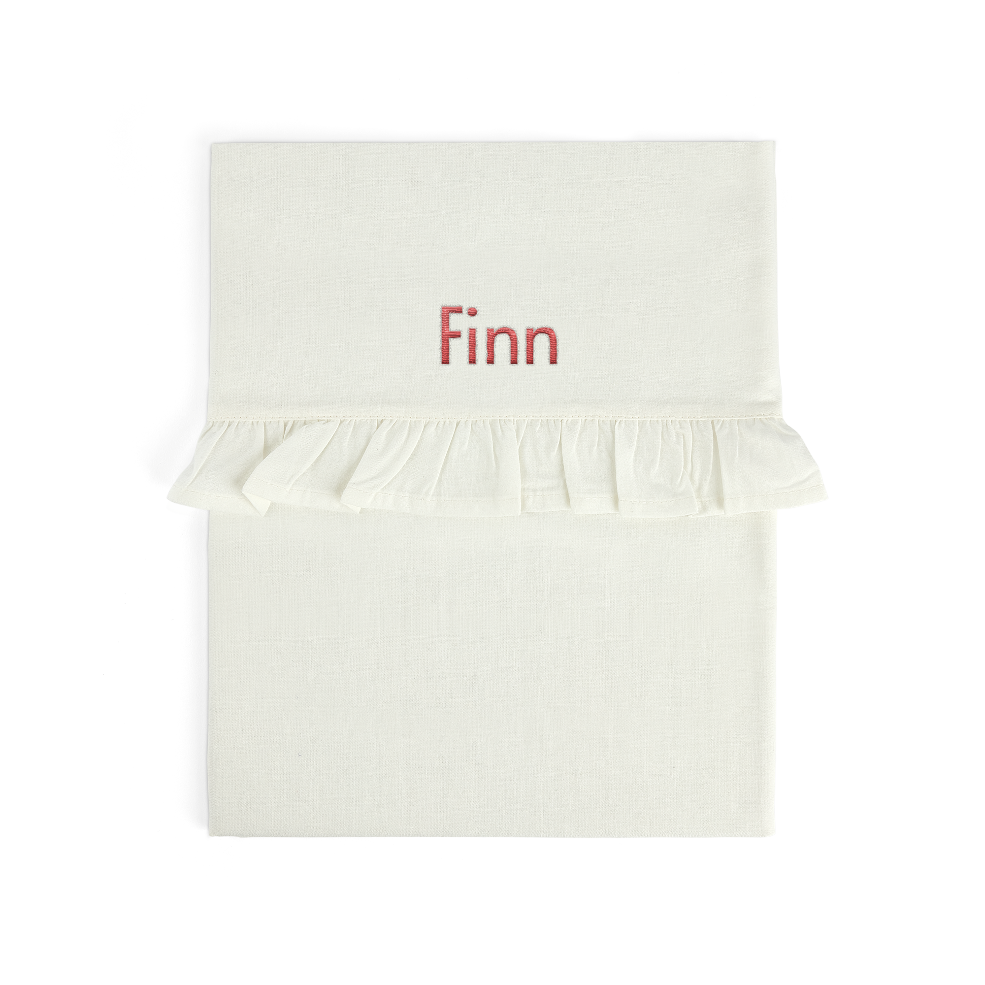 Sábana de moisés blanca con volante, bordada con el nombre "Finn" en rojo.