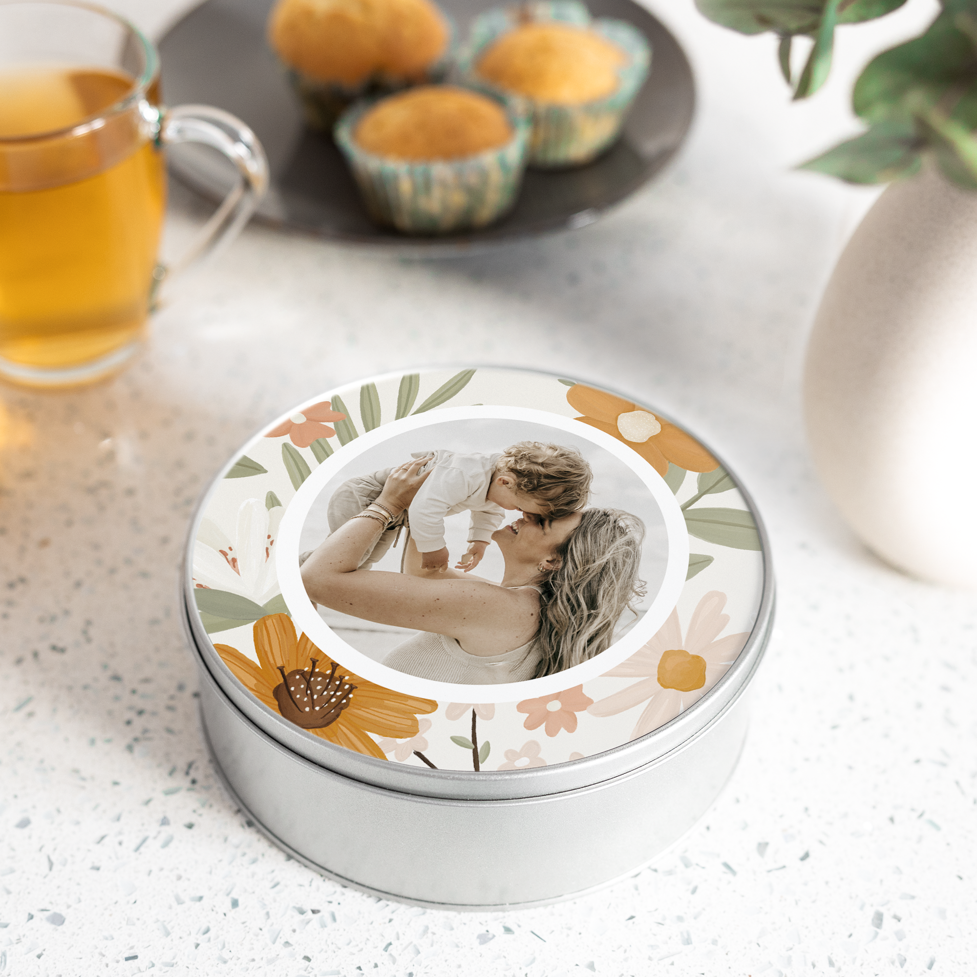 Lata de metal redonda personalizada con una foto de mamá y bebé, rodeada de un estampado floral. ¡Sorpréndelos con una lata de recuerdos con tu foto favorita!
