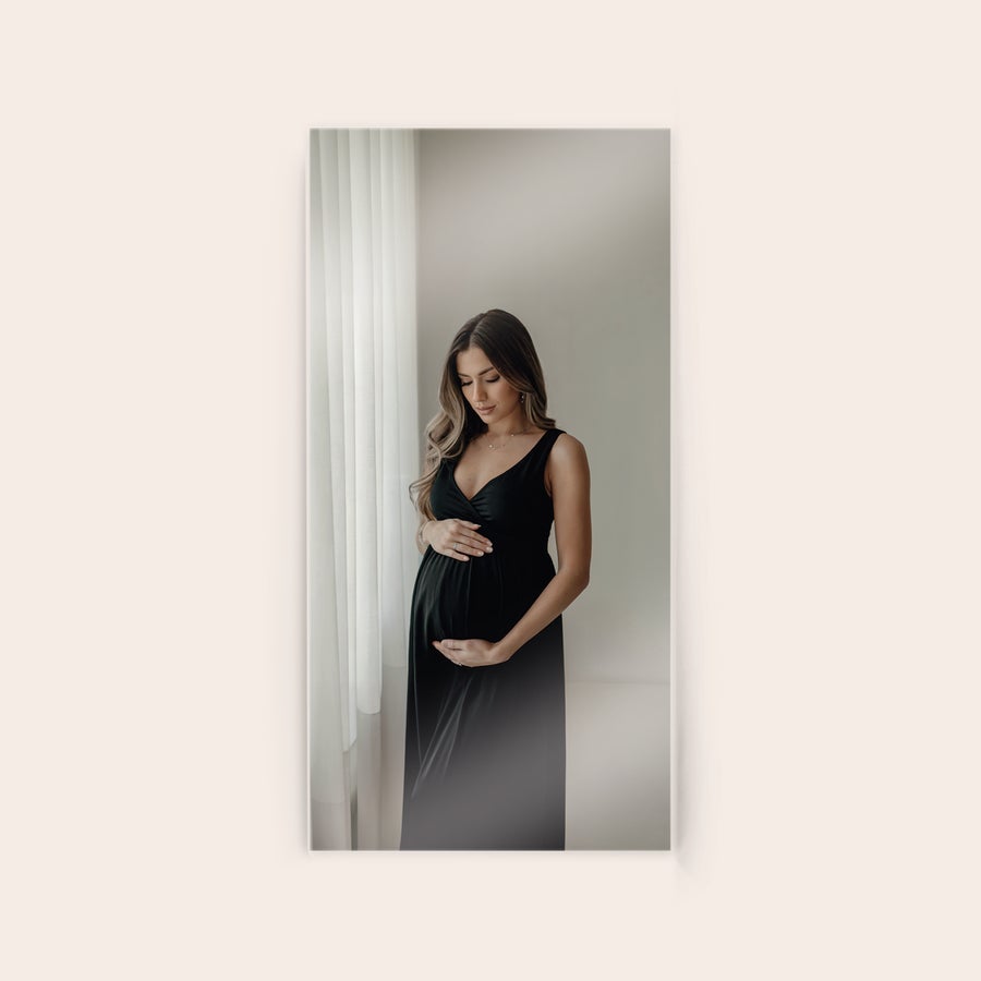 Tableau photo plexiglas Photo imprimée sur plexiglas dune femme enceinte en robe noire, les mains sur son ventre. Originalité et éclat de la photo.