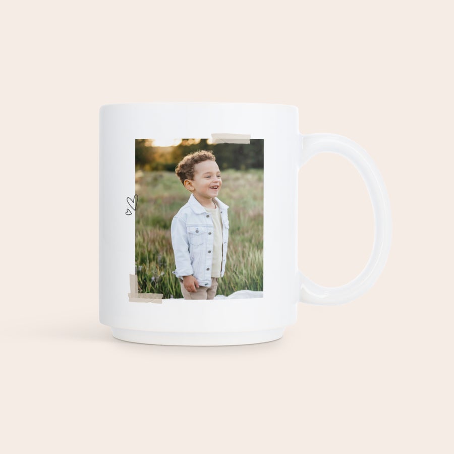 Stapelbare mokken bedrukken Witte stapelbare fotomok bedrukt met een vrolijke foto van een lachende jongen in een veld, met kleine hartjes op de zijkant.