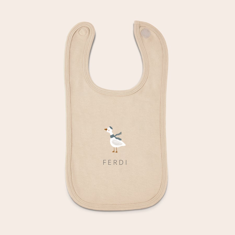 Baby bib Personlig smekke i beige med et trykt bilde av en and med blått skjerf og navnet FERDI