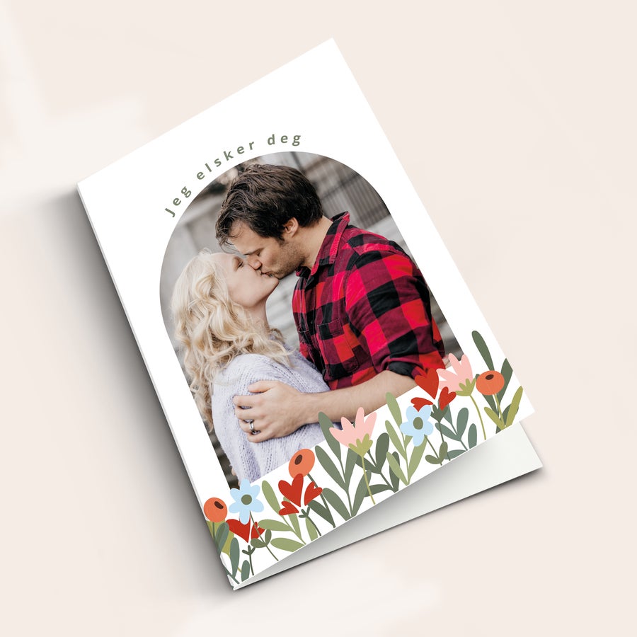 Personlig kort med bilde Personlig valentindagskort med bilde av et kyssende par, trykt med teksten Jeg elsker deg og blomster.