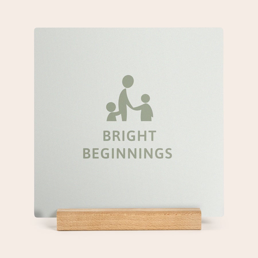 Wooden Photo Tile Square Forex Photo Tile with a custom "Bright Beginnings" graphic, printed with text and an image of two children and an adult, on a wooden stand.