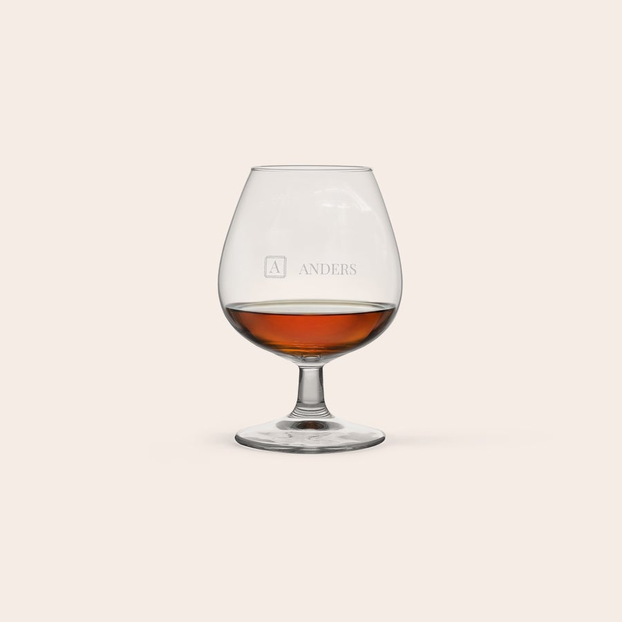 Cognac glas Ett elegant cognacglas med gravyr av namnet Anders och ett monogram fyllt med gyllenbrun dryck