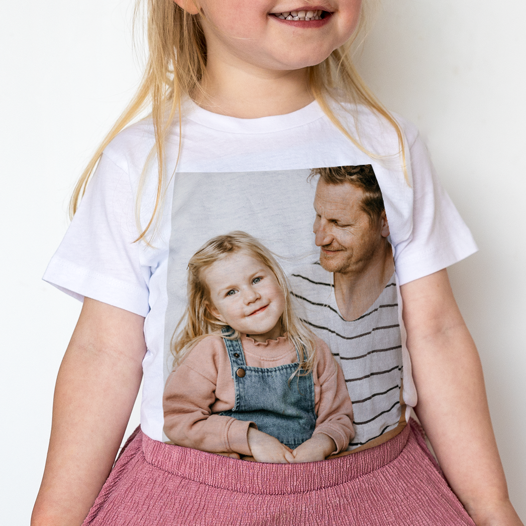 Niña con camiseta blanca para niños, impresa con una foto personalizada de ella y su padre.