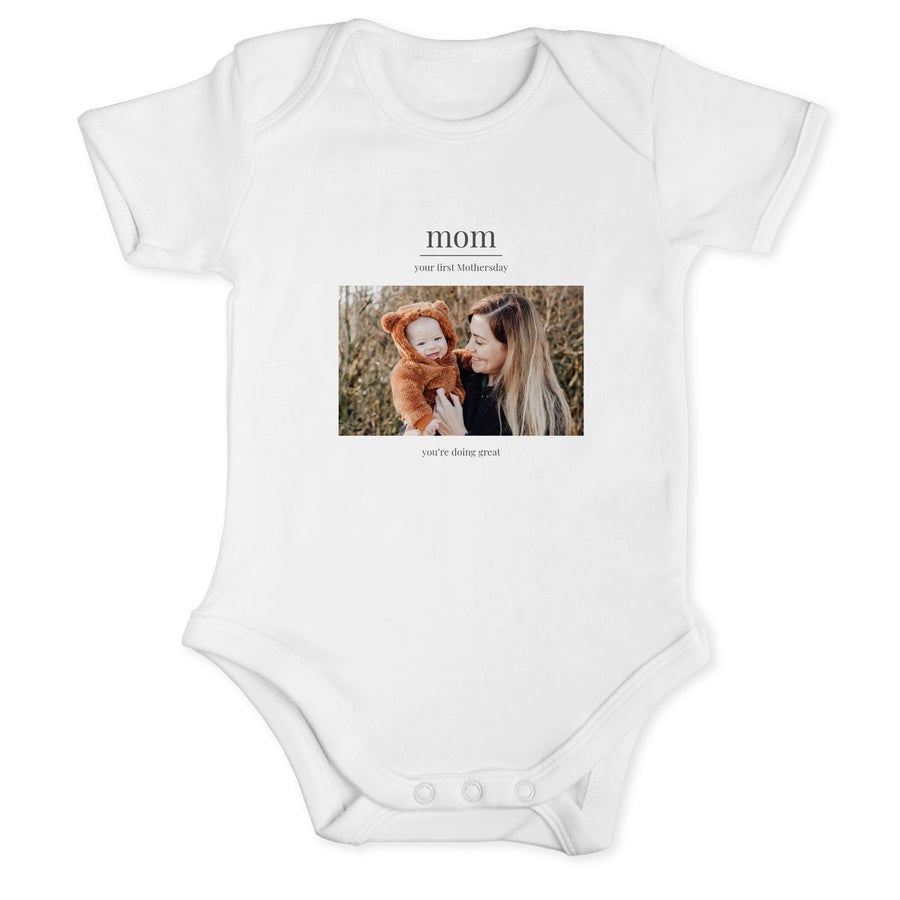 Hvit onesie trykt med bilde av mor og baby, teksten "mom you're first Mothersday you're doing great"