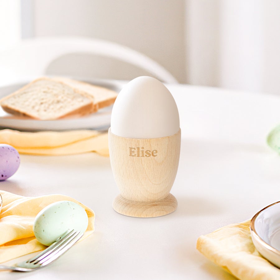 Personalised egg cup Personalised egg cup made of beech wood with Elise engraved on the side, holding a white egg