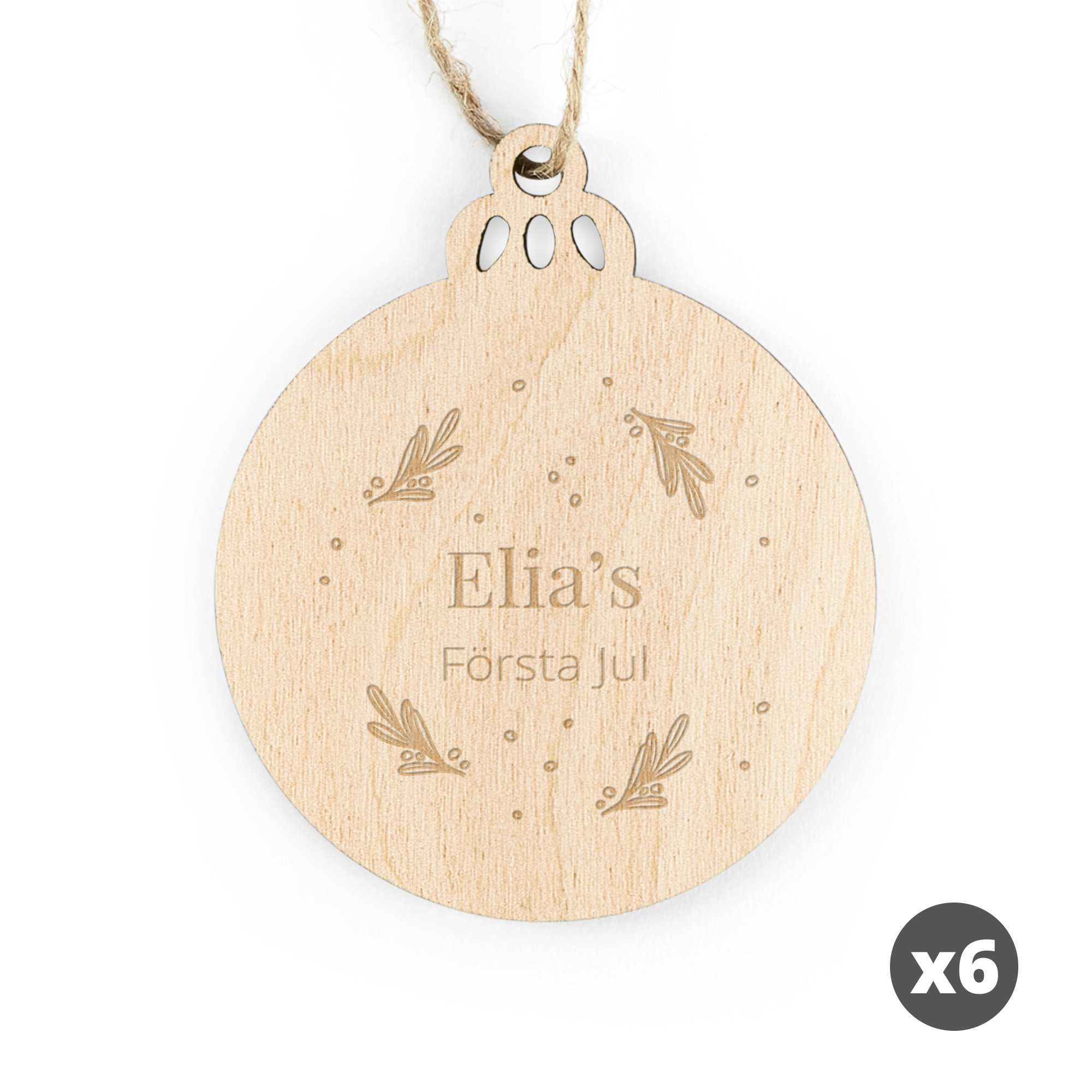 Cirkulär graverad juldekoration i trä med texten "Elias Första Jul" och mönster.