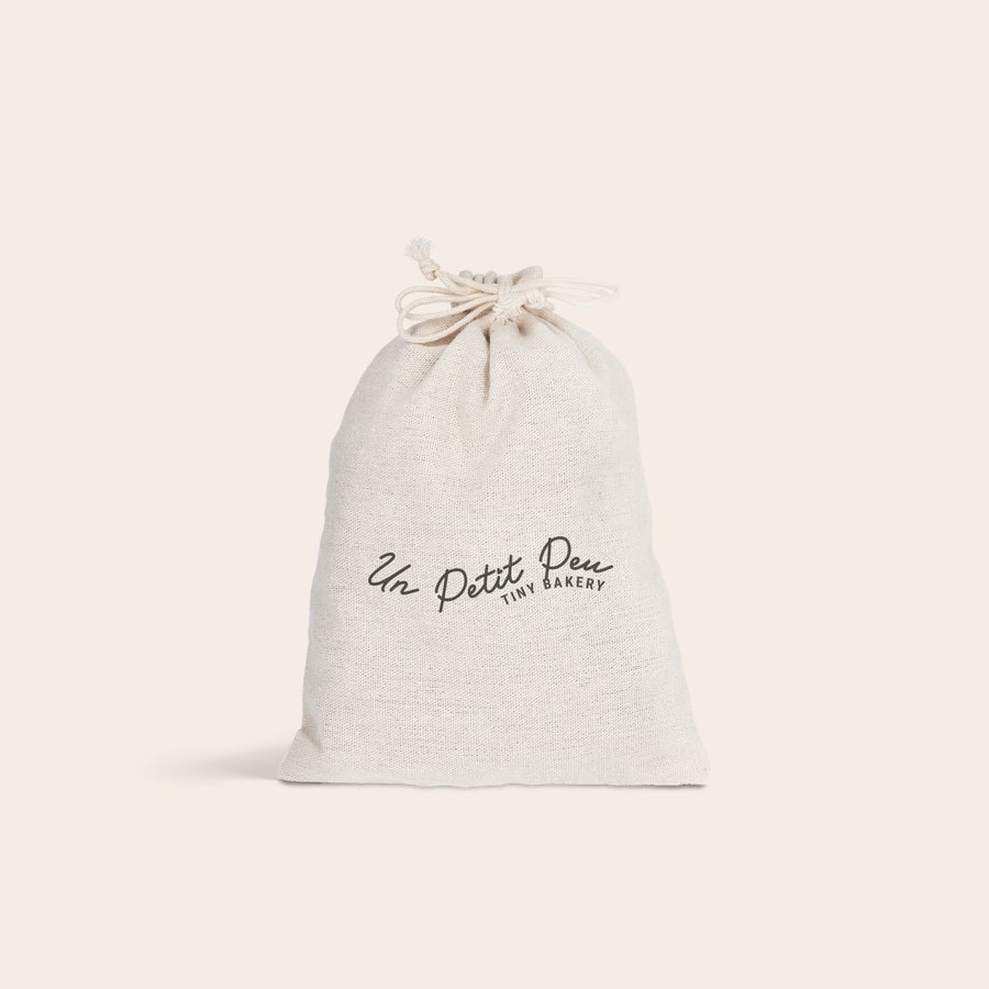 Katoenen zakje Gepersonaliseerd katoenen zakje bedrukt met tekst Un Petit Peu Tiny Bakery, ideaal voor cadeaus.