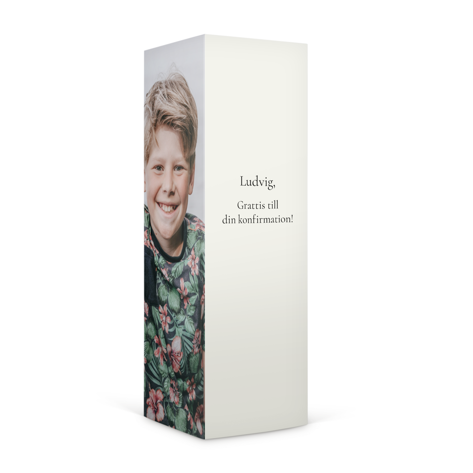 En personlig presentförpackning med en tryckt bild av en leende pojke, texten "Ludvig, Grattis till din konfirmation!" och utrymme för Haribo godis
