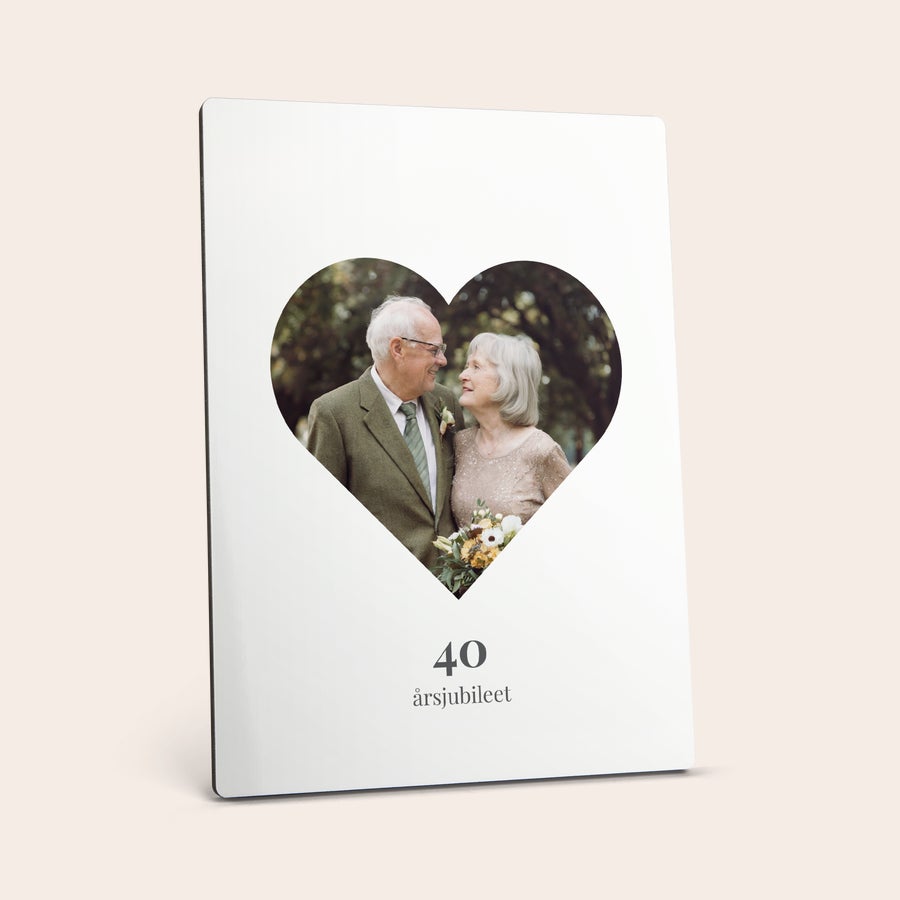 Foto på hardboard Fotostativ med bilde av et eldre par trykt i en hjerteform, med teksten 40 årsjubileum under.