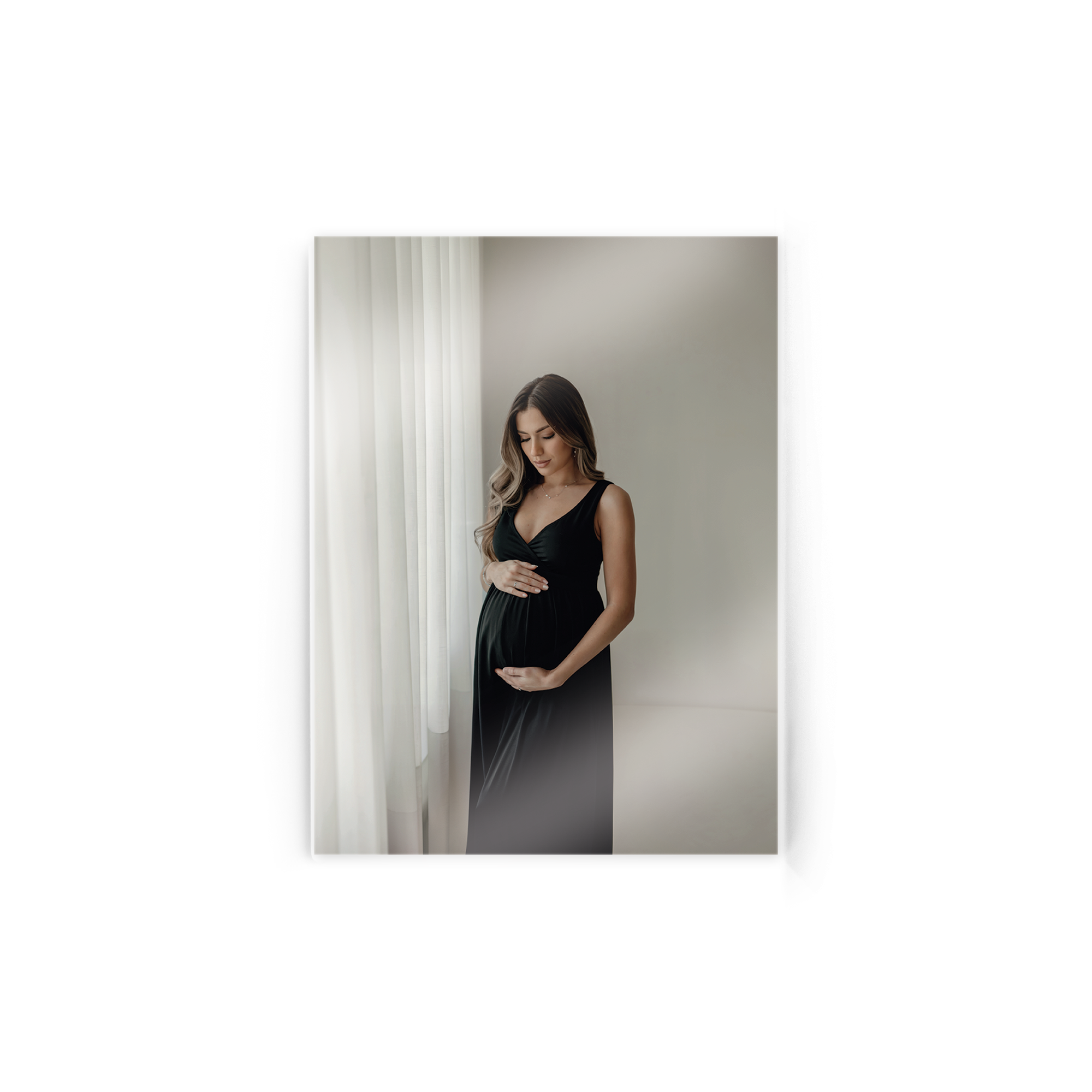 Foto em acrílico impressa com uma imagem de mulher grávida em vestido preto, olhando para a barriga.