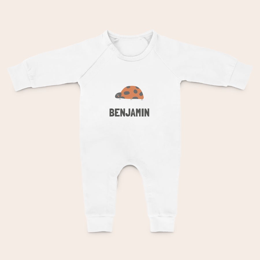 Detská Kombinéza s Personalizáciou Biely personalizovaný detský overal s potlačou lienky a menom Benjamin pre naťahovanie a kopanie do tých bacuľatých nôh.