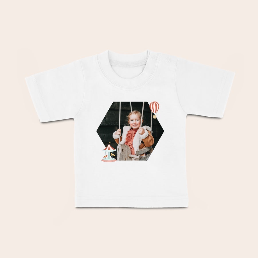 Baby T-shirt Vit babyskjorta med ett tryckt hexagonalt foto av ett leende barn med karusell och ballongmotiv. Ditt lilla barn blir så fin i en glad babyskjorta med ett namn eller en bild.