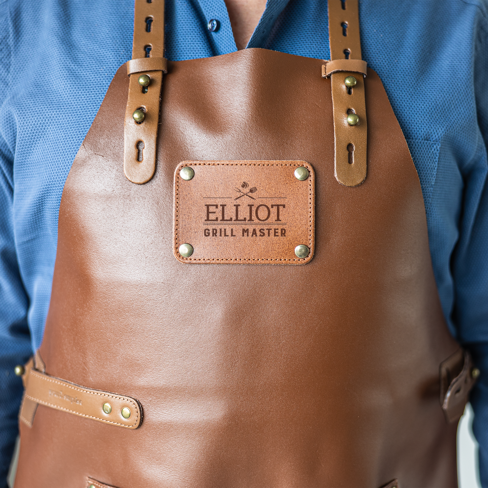 Personalised Leather Apron - Brown, engraved with the name Elliot Grill Master, featuring adjustable straps.