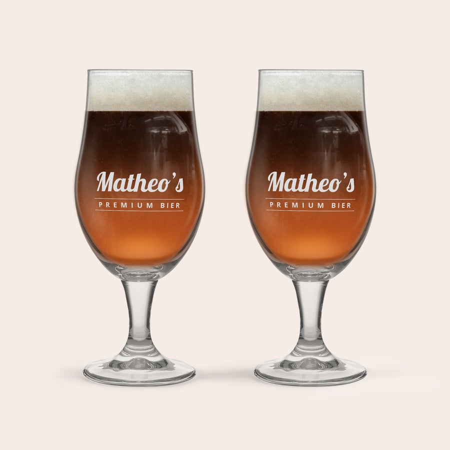 Speciaalbier glas met naam graveren Twee speciaal bierglazen, gegraveerd met de naam "Matheo's Premium Bier", gevuld met donker bier en schuimkraag.