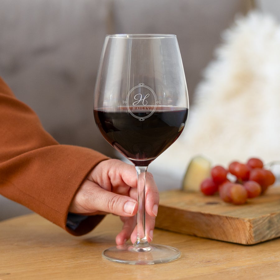 Glass - Vinho Tinto Copo de vinho personalizado com nome e letra H gravados, segurado por uma mão, com vinho tinto.