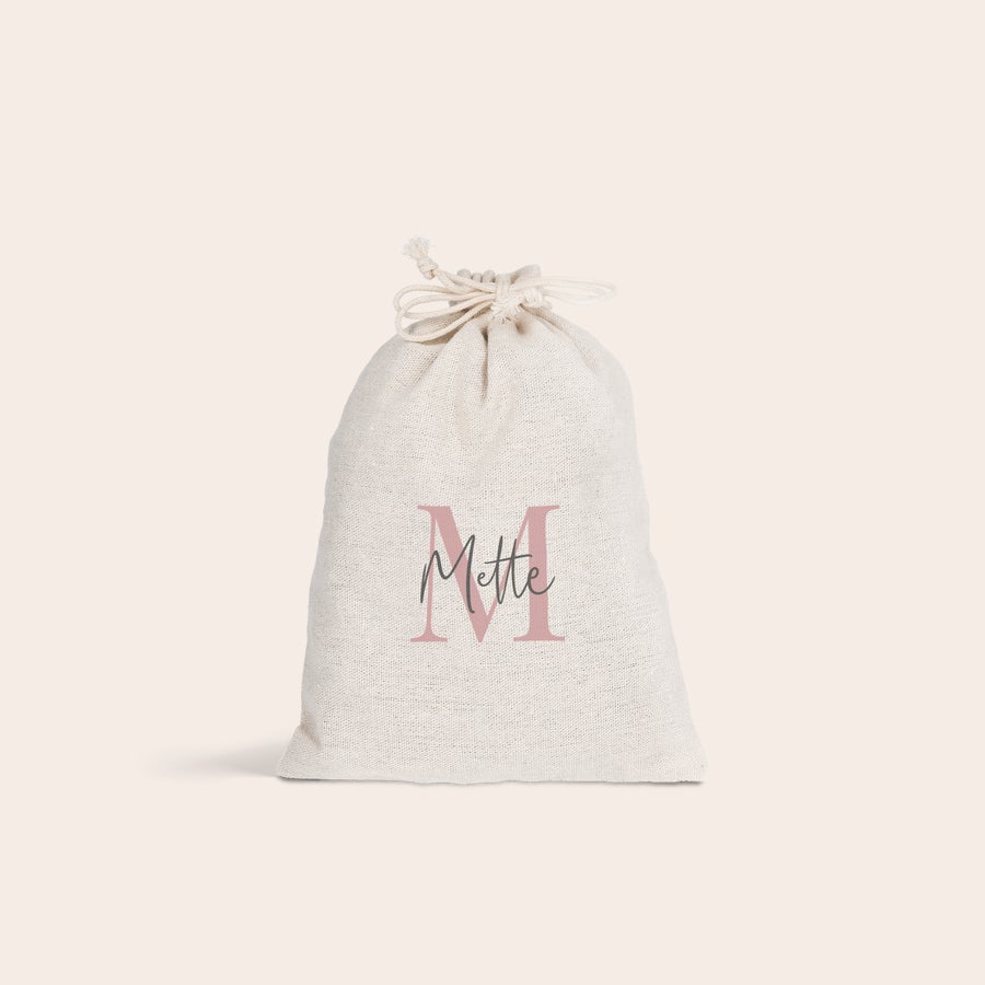 Gavepose i stof En personlig gavepose i stof med navnet Mette printet i lyserød og grå, et unikt touch til gaver.