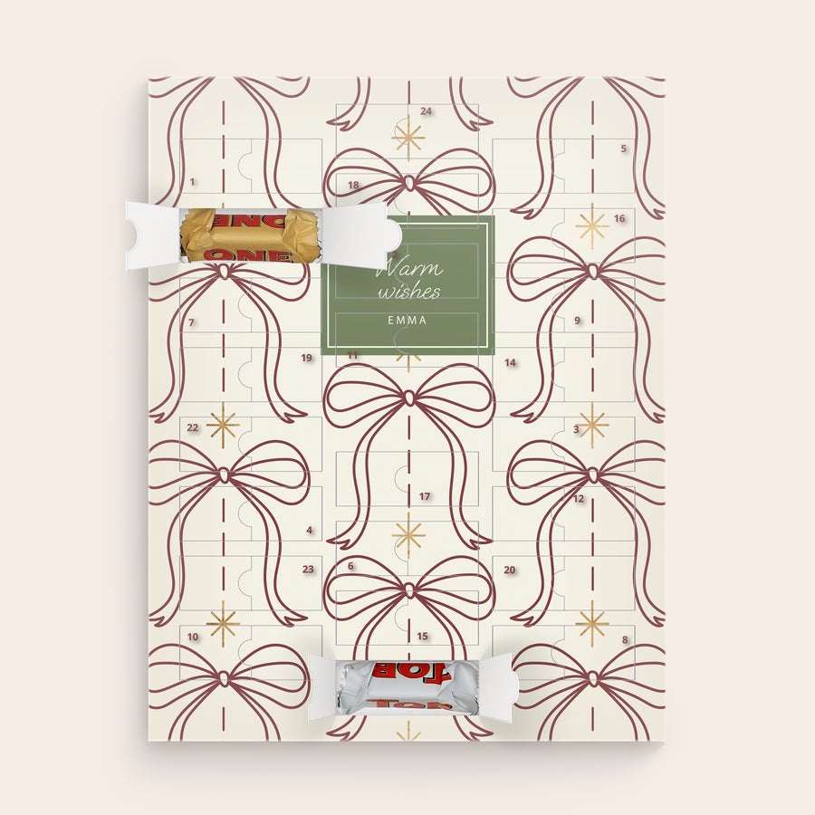 Calendario dell'Avvento Personalizzato - Toblerone 2025 Calendario dellavvento personalizzato con motivo a fiocchi, due scomparti aperti con cioccolatini Toblerone e il testo stampato Warm wishes Emma per il conto alla rovescia per Natale