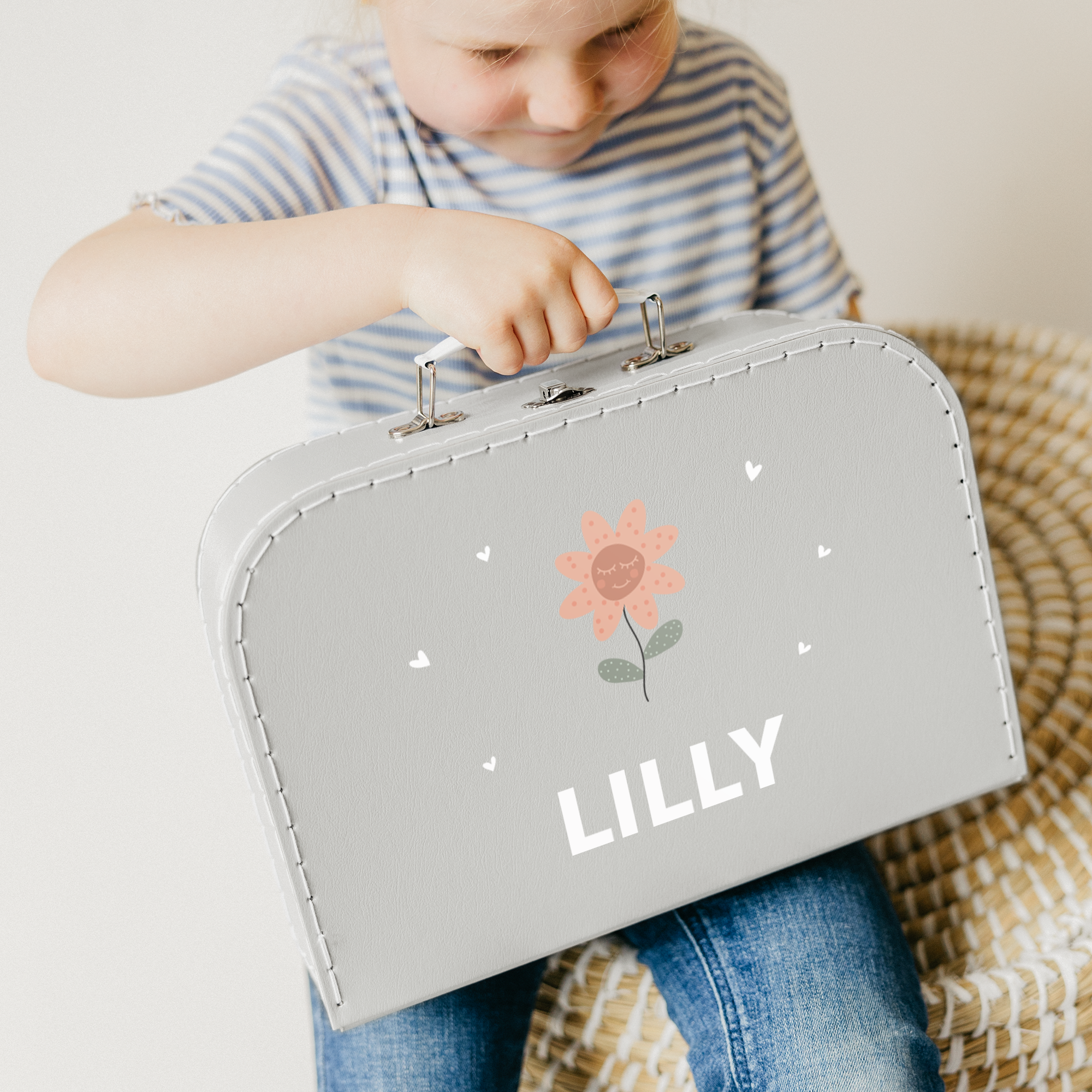 Grå leksaksväska i kartong med namnet Lilly tryckt, en glad blomma och små hjärtan. Denna vackra tryckta leksaksväska är den perfekta detaljen i alla barns sovrum.