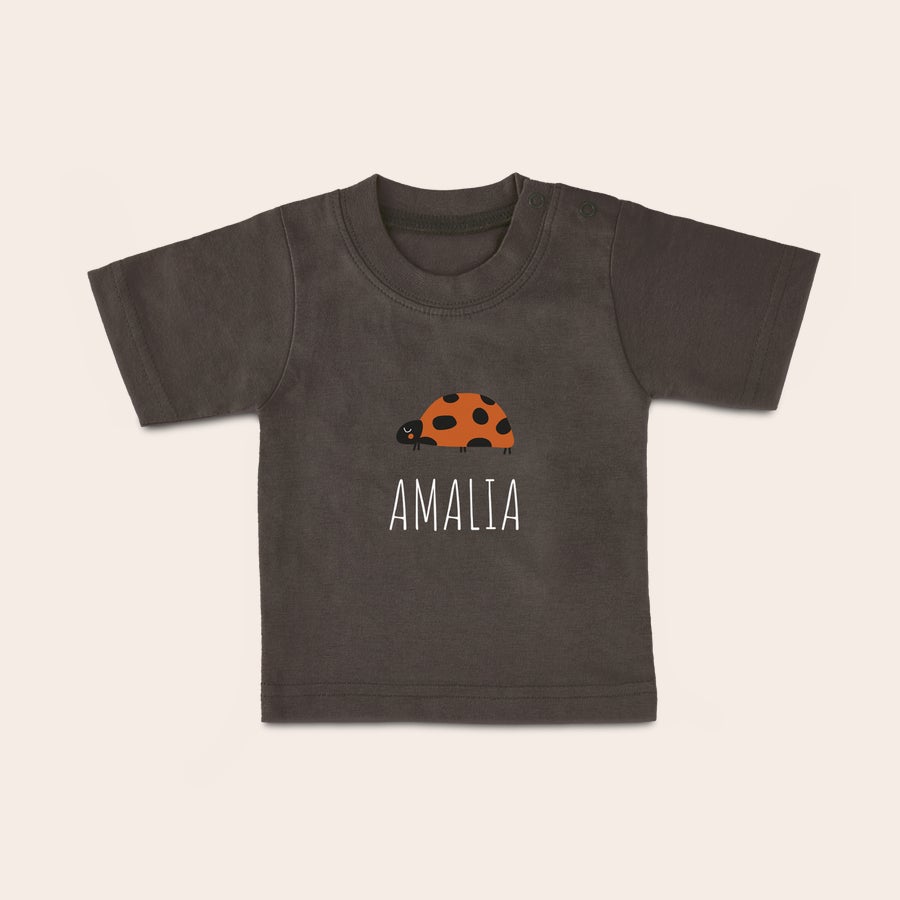 Baby t shirt bedrucken Ein Baby T-Shirt mit Namen Amalia und einem Marienkäfer-Motiv, aufgedruckt auf dunklem Stoff. Dein Kleines ist ganz modern mit diesem individuellen T-Shirt.