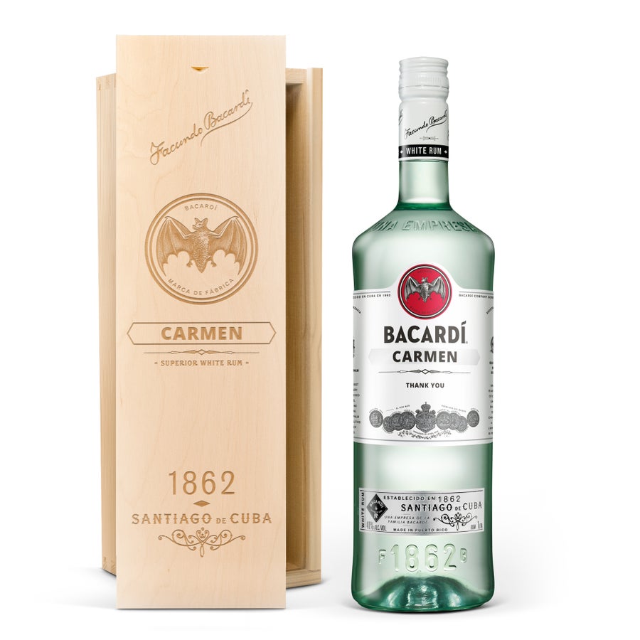 Bacardi Carta Blanca rum személyre szabott címkével, "Carmen" és "Thank You" felirattal, egy gravírozott fadoboz mellett.