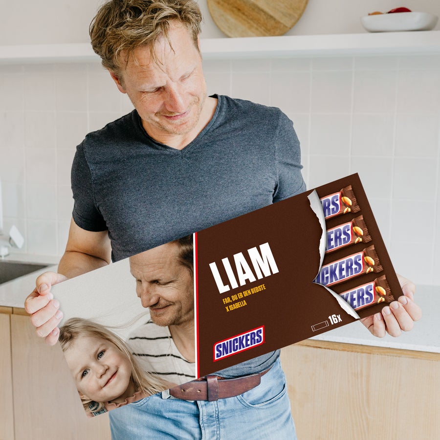 Mega Snickers Chokolade med navn og billede Mand holder personlig Mega Snickers trykt med navn Liam og et foto af ham med et barn