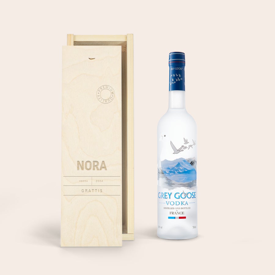 Vodka Grey Goose i en personlig låda En flaska grå gåsvodka bredvid ett anpassat tryckt fodral i trä med texten Nora 2004 Grattis
