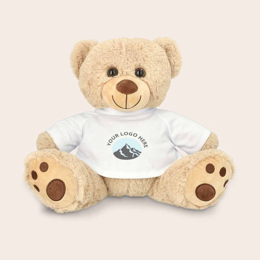 Personalised cuddly toy bear A brown teddy bear wearing a white T-shirt with a custom printed logo design, ready to surprise them